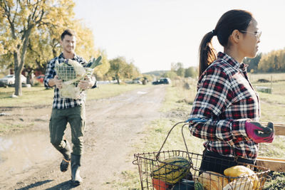 Male and female farmers carrying baskets of organic vegetables at field