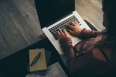 Young woman working on laptop at home. female hands typing on computer keyboard making video call  