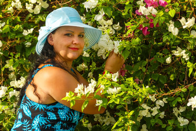 Young woman standing against plants