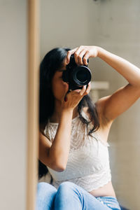 Midsection of woman holding camera at home