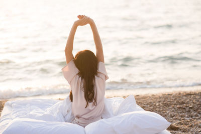 Woman wearing pajamas wake up in bed wuth duver and pillow over nature sea background outdoors.