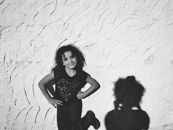 Portrait of smiling girl dancing against wall