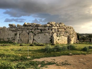 Stone wall on field against sky