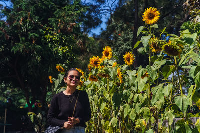 Portrait of young woman standing amidst plants