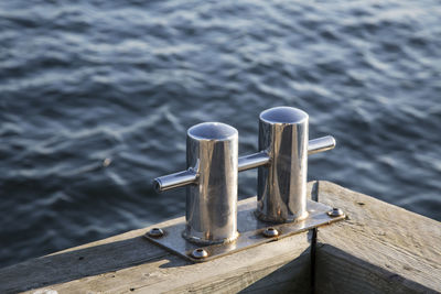 High angle view of metallic bollard at harbor by sea