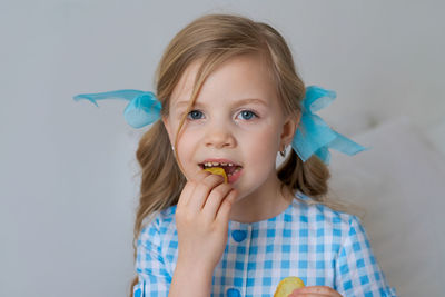 Portrait happy little caucasian girl eating crispy potato chips on gray