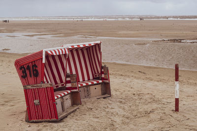 Deck chairs on beach against sky