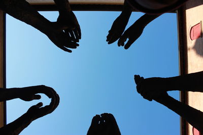 Low angle view of silhouette people against clear sky