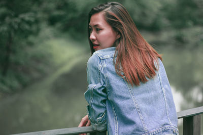 Young woman looking away while standing outdoors