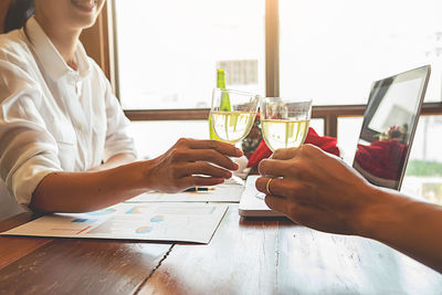 Midsection of woman holding drink on table