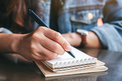 Close-up of woman writing in book on table