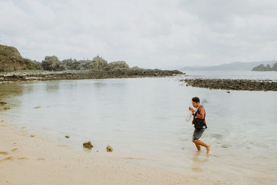 Full length of boys on beach against sky