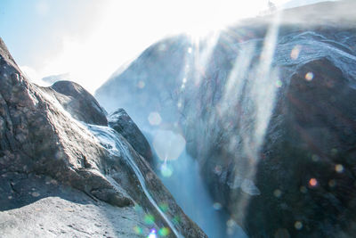 Scenic view of waterfall and mountains against sky