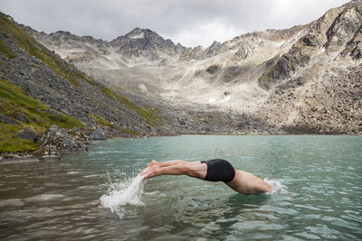 Man dives in for swim in upper reed lake, talkeetna mountains, alaska