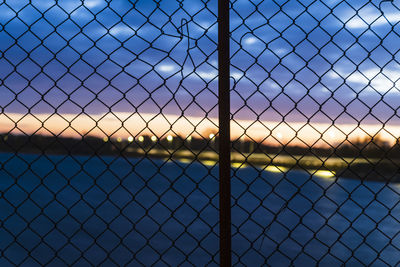 Sunset sky seen through chain link fence
