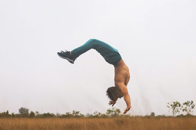 Full length of man skateboarding on field against clear sky