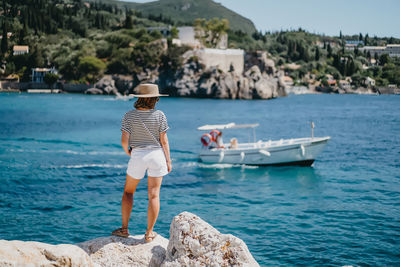 Rear view of man standing on rock by sea