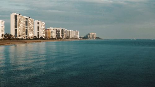 Sea by cityscape against sky