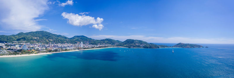 Panoramic view of sea and mountains against blue sky