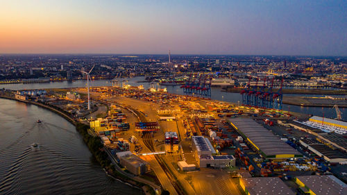 High angle view of illuminated cityscape by river against sky