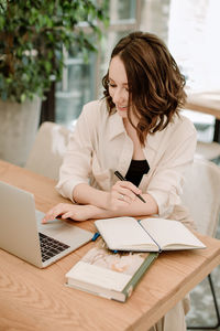 Woman using mobile phone while sitting on table