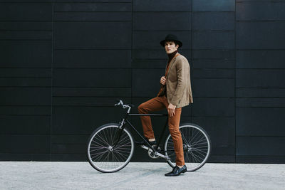 Full length portrait of teenage girl riding bicycle against wall