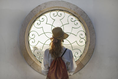 Rear view of woman looking through window