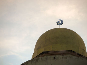 Low angle view of cross on building against sky