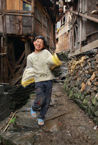 Portrait of a smiling young woman standing against building