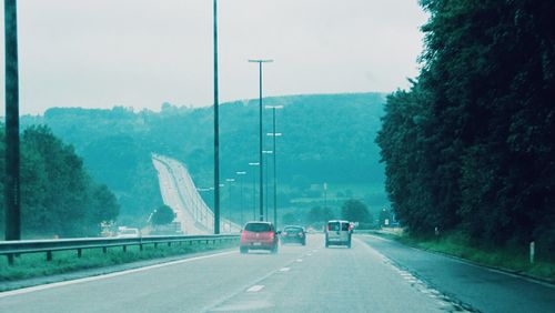 Cars on highway by road against sky