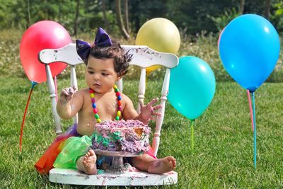 Cute baby girl sitting on chair outdoors during birthday party 