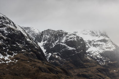 Scenic view of snowcapped mountains against cloudy sky