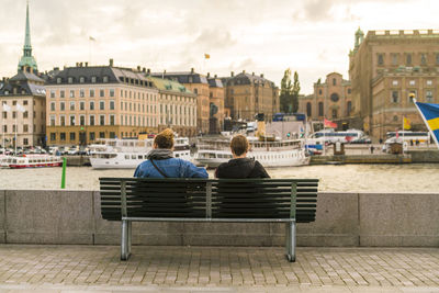 Two females sitting by gamla stan on the water