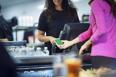 Midsection of customer paying bill thought smart phone in restaurant