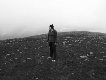 Woman standing on mountain against sky during foggy weather