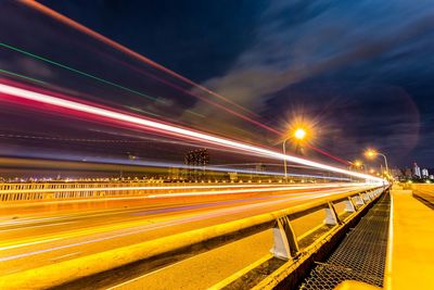 Light trails on road in city against sky at night