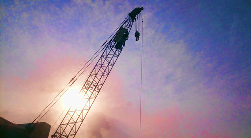 Low angle view of silhouette cranes against sky