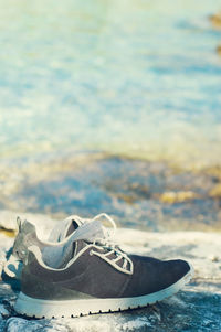 Close-up of shoes on water against sky