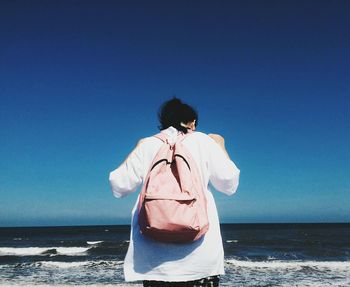 Rear view of man looking at sea against clear sky