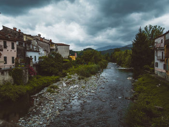 River amidst houses and buildings against sky