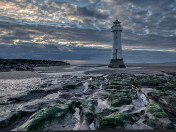 Lighthouse in sea against sky