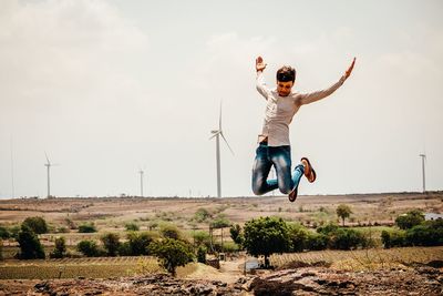 Man jumping on field against sky