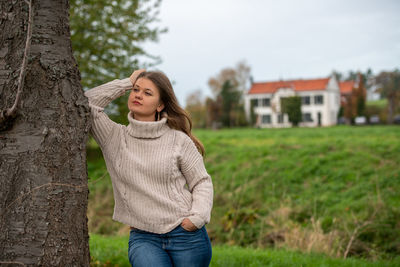 Woman standing on tree trunk against plants