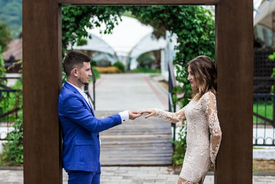 Side view of man and woman standing against tree