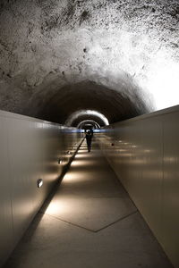 Rear view of person walking in tunnel