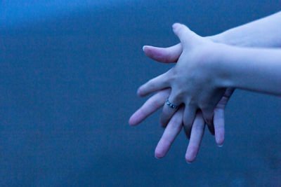 Close-up of hand against blue sky