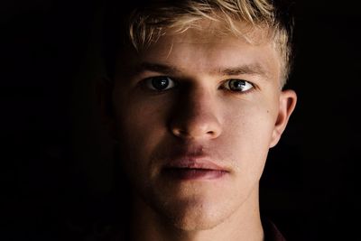 Close-up portrait of young man against black background