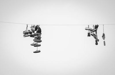 Low angle view of people hanging on rope against clear sky