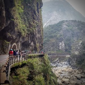 People at riverbank against mountains