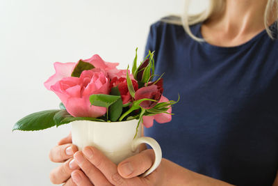 Midsection of woman holding bouquet against white background